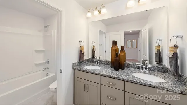 a bathroom with a granite countertop sink a mirror and a bathtub