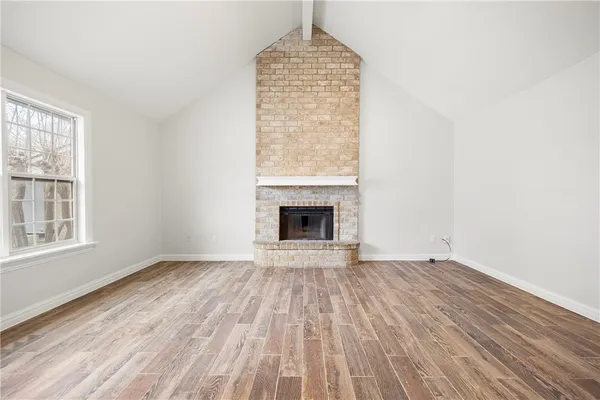 an empty room with wooden floor a fireplace and windows