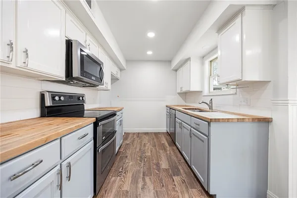 a kitchen with stainless steel appliances granite countertop a sink a stove and a wooden floors