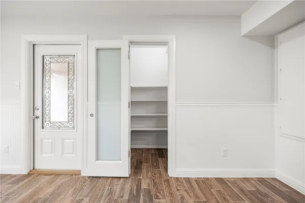 a view of an empty room with wooden floor and closet