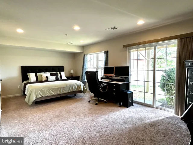 a bedroom with a bed and two large window