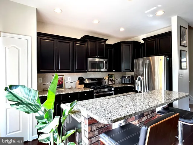 a kitchen with stainless steel appliances kitchen island granite countertop a refrigerator and stove