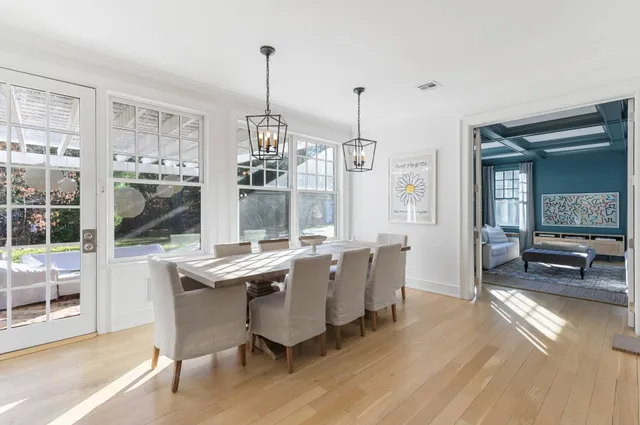 a view of a dining room and livingroom with furniture wooden floor a chandelier