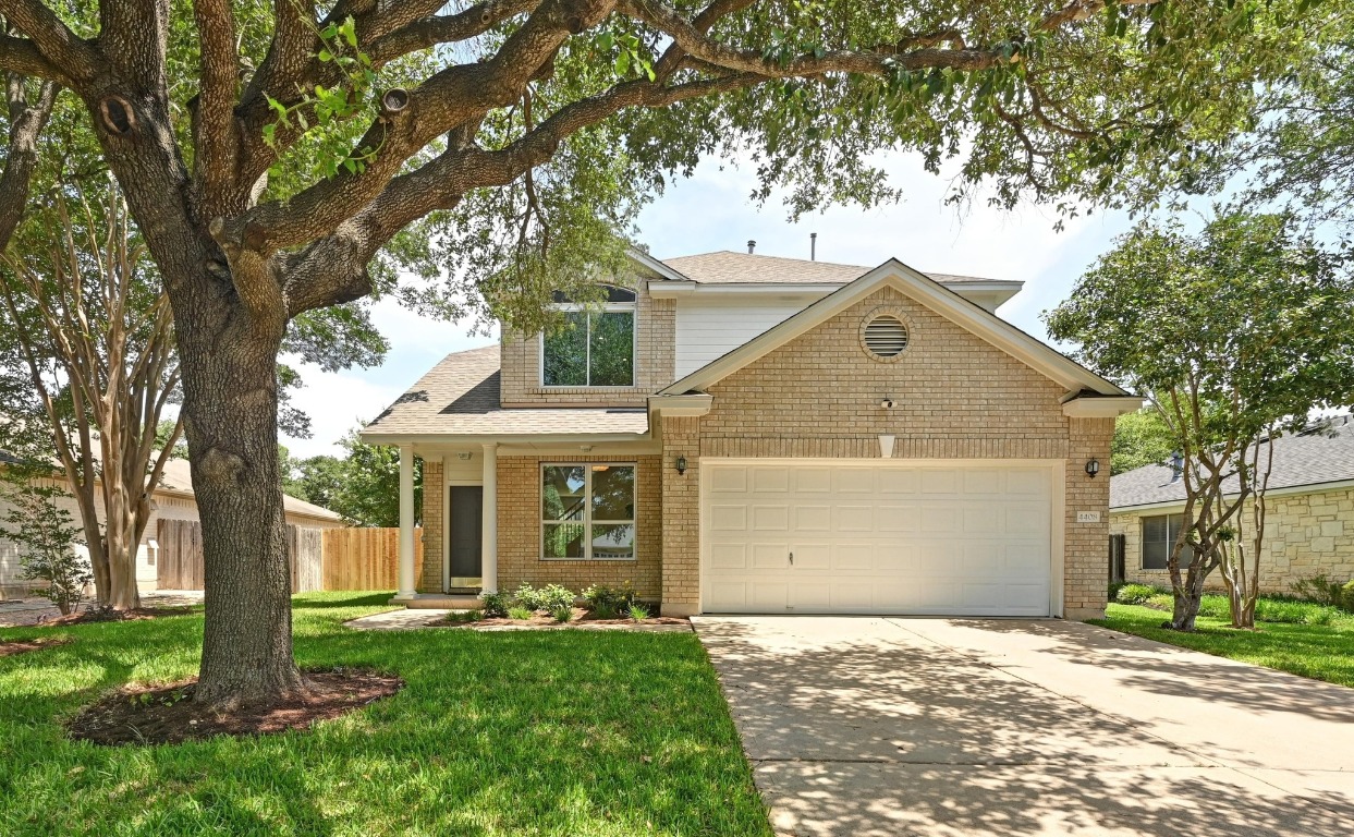 a view of a yard in front of a house with a large tree