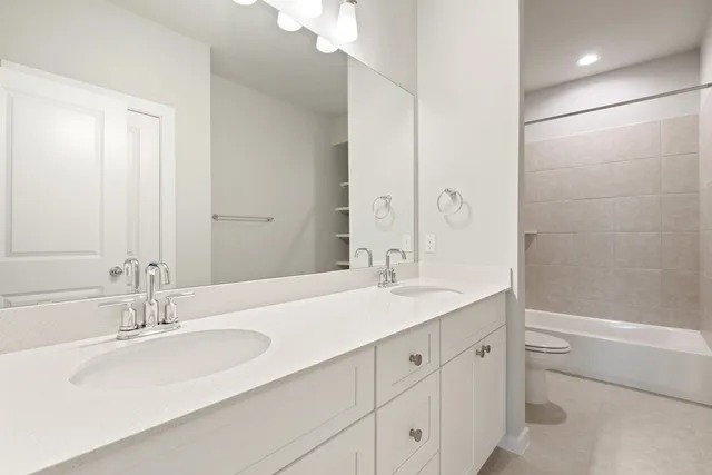 a bathroom with a sink double vanity granite tub shower and a mirror