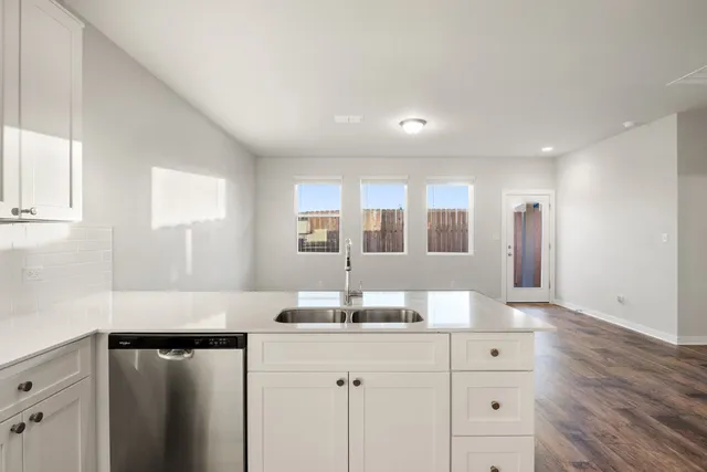 a kitchen with kitchen island sink stove and white cabinets with wooden floor