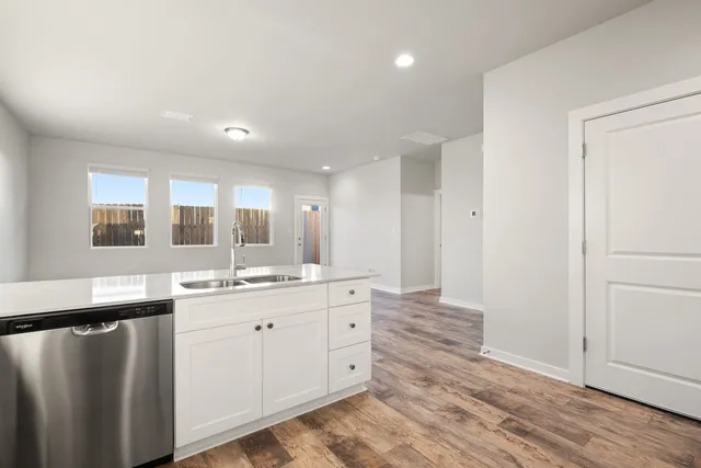 a view of an empty room with wooden floor and windows