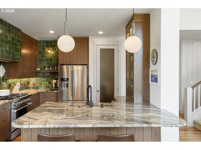 a view of a kitchen with kitchen island stainless steel appliances granite countertop a sink and cabinets