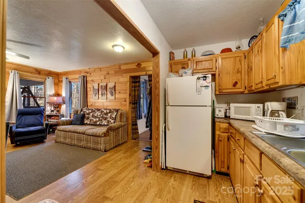 a kitchen with stainless steel appliances granite countertop a refrigerator a microwave oven a sink and dishwasher with wooden floor