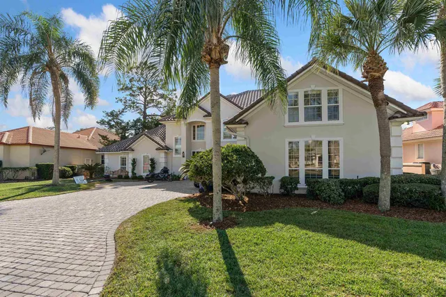 front view of a house with a yard and palm trees