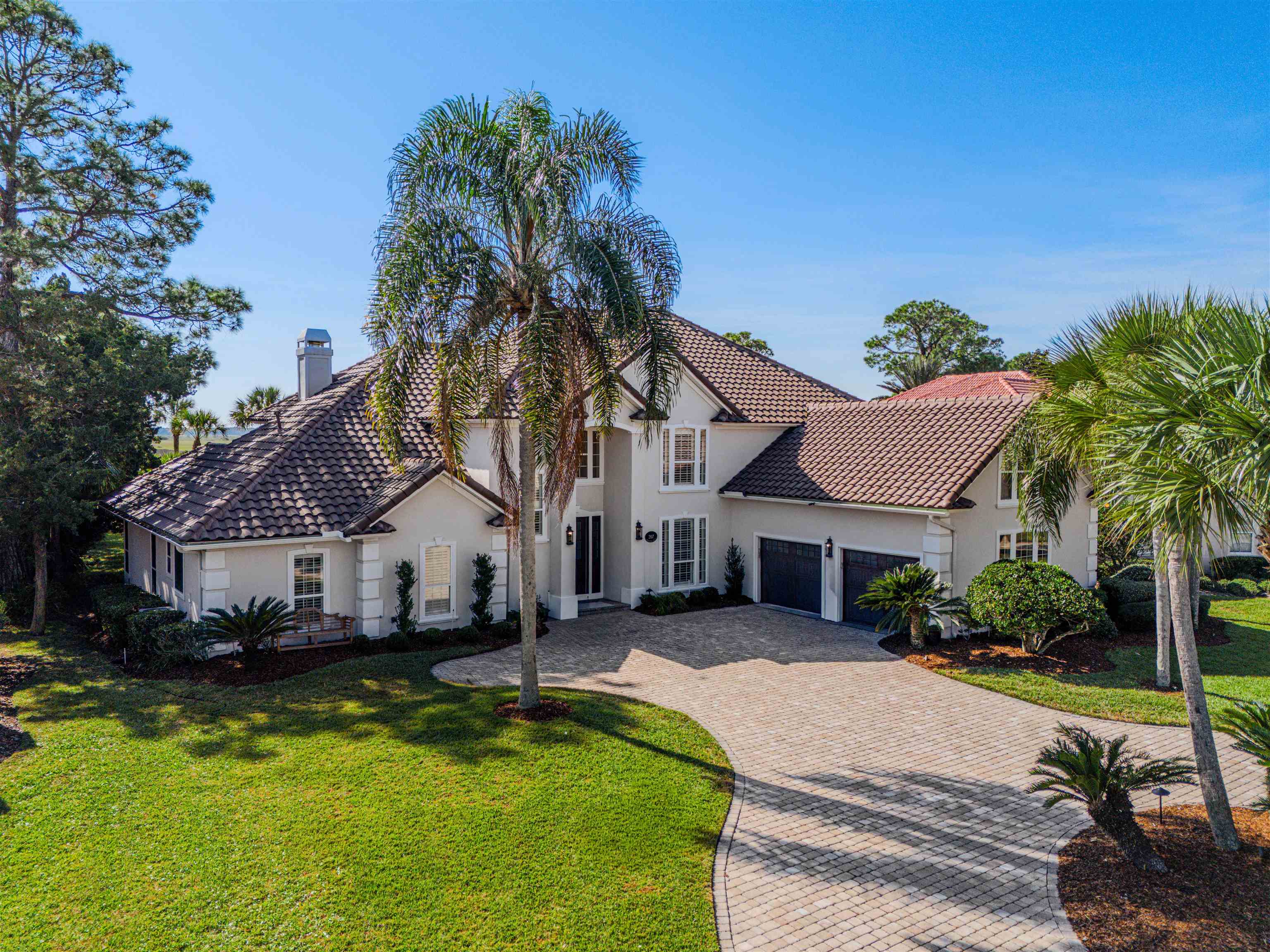 207 Marshside Drive St. Augustine, FL 32080 - Photo 4 of 87 Mediterranean / spanish-style house featuring a front lawn, decorative driveway, an attached garage, stucco siding, and a chimney