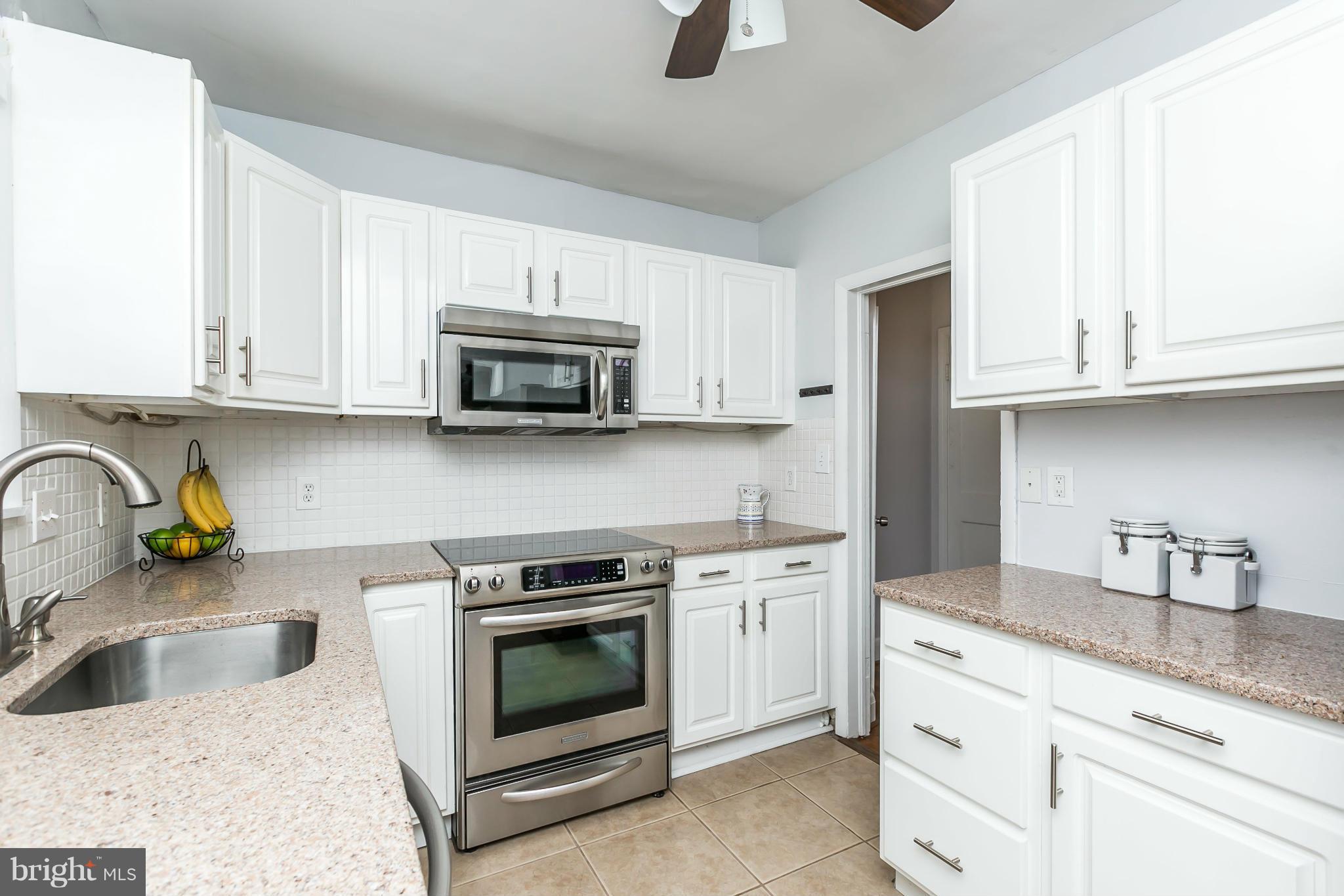 1947 Edgewood Road Baltimore, MD 21286 - Photo 13 of 28 a kitchen with stainless steel appliances granite countertop a sink a stove a microwave and wooden cabinets