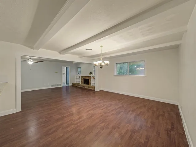 an empty room with wooden floor cabinet and windows