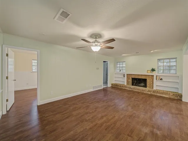 an empty room with fireplace fan and windows