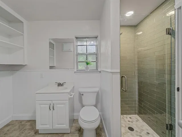 a bathroom with a toilet a sink a shower and mirror