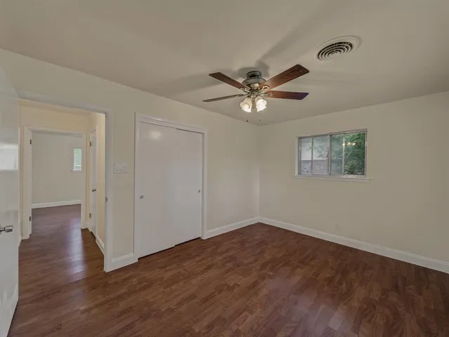 an empty room with wooden floor and ceiling fan