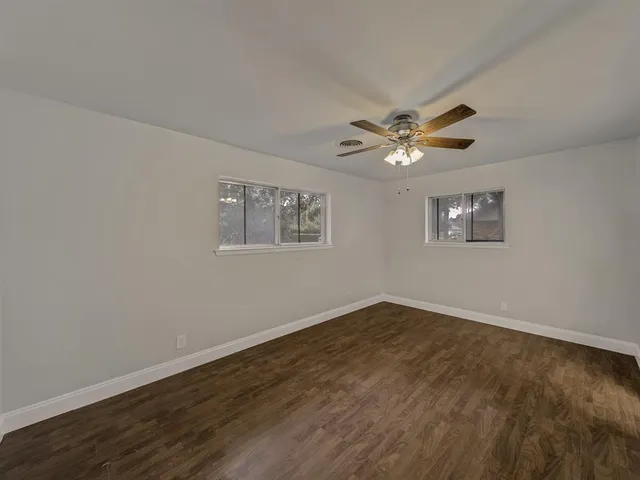 an empty room with wooden floor and ceiling fan