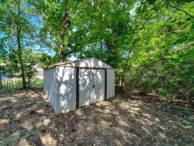 a backyard of a house with large trees and swing