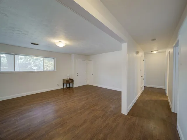 a view of an empty room with window and wooden floor