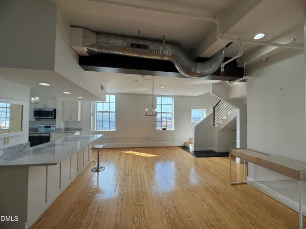 a view of a room with wooden floor and a kitchen