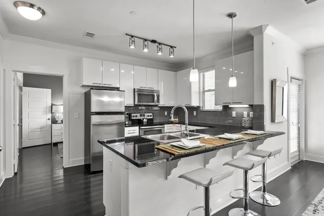 a kitchen with refrigerator a sink and chairs
