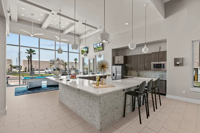 a dining hall with stainless steel appliances kitchen island granite countertop a table chairs and a view of living room
