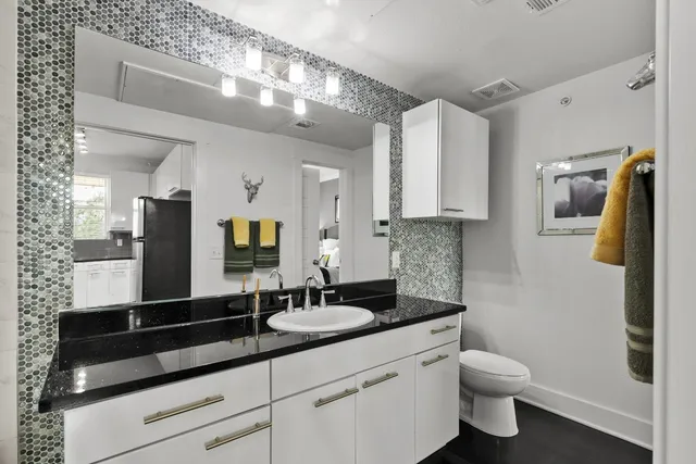 a bathroom with a granite countertop sink a toilet a mirror and shower