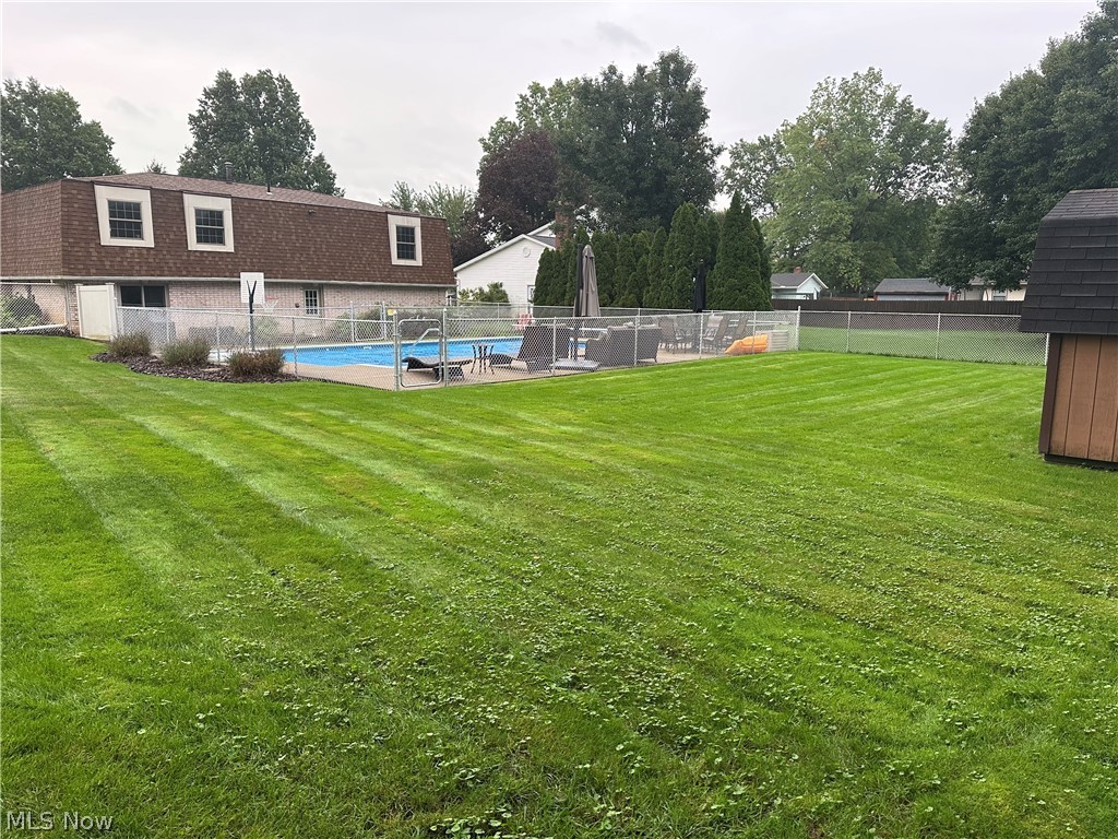 1619 Reed Street Canal Fulton, OH 44614 - Photo 4 of 21 Expansive lawn featuring an in-ground swimming pool with surrounding fence, mature trees, and a storage shed