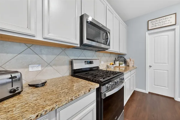 a kitchen with granite countertop cabinets and steel stove top oven