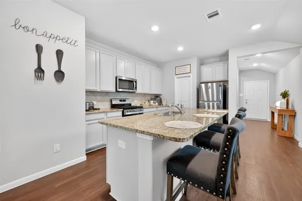 a kitchen with a table chairs refrigerator and microwave