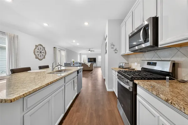 a kitchen with stainless steel appliances granite countertop a stove a sink and a microwave
