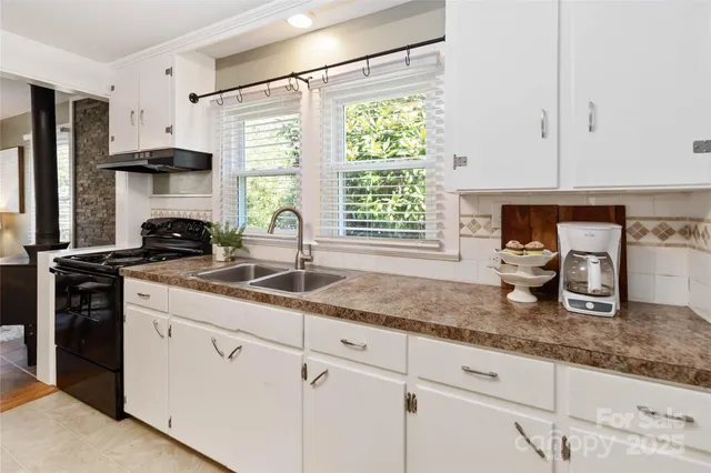 a kitchen with granite countertop a sink white cabinets and window