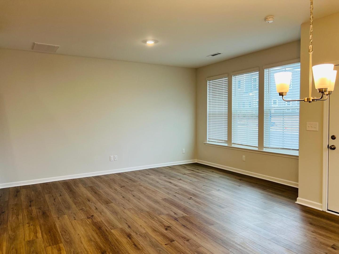 183 Chesapeake Commons Street Garner, NC 27529 - Photo 5 of 26 an empty room with wooden floor and windows
