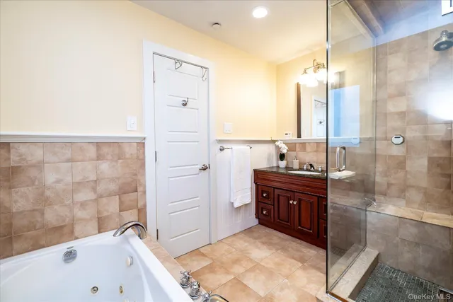 a spacious bathroom with a tub sink and mirror
