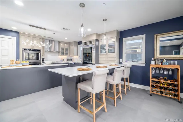 a room with stainless steel appliances kitchen island granite countertop a table chairs and a refrigerator