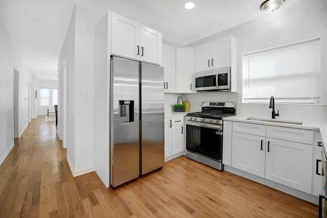 a kitchen with white cabinets stainless steel appliances and wooden floors