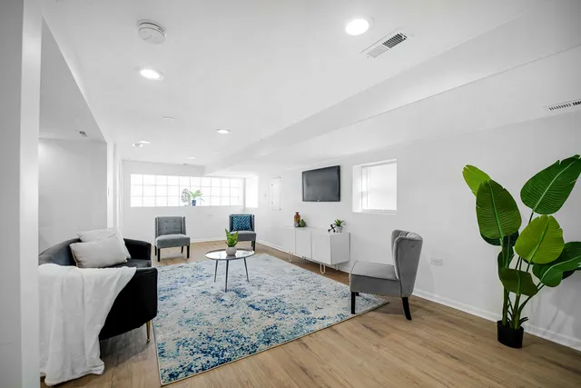 a living room with furniture floor to ceiling window and wooden floor