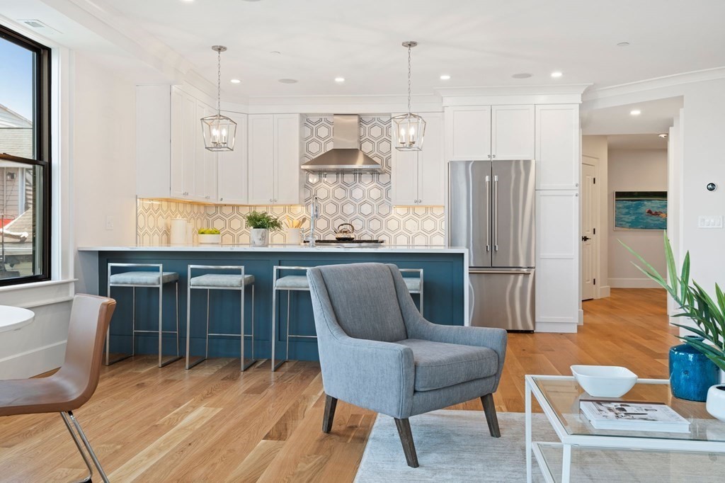9 Glover Court, Unit 6 Boston, MA 02127 - Photo 11 of 34 a kitchen with stainless steel appliances kitchen island granite countertop a dining table chairs and a refrigerator