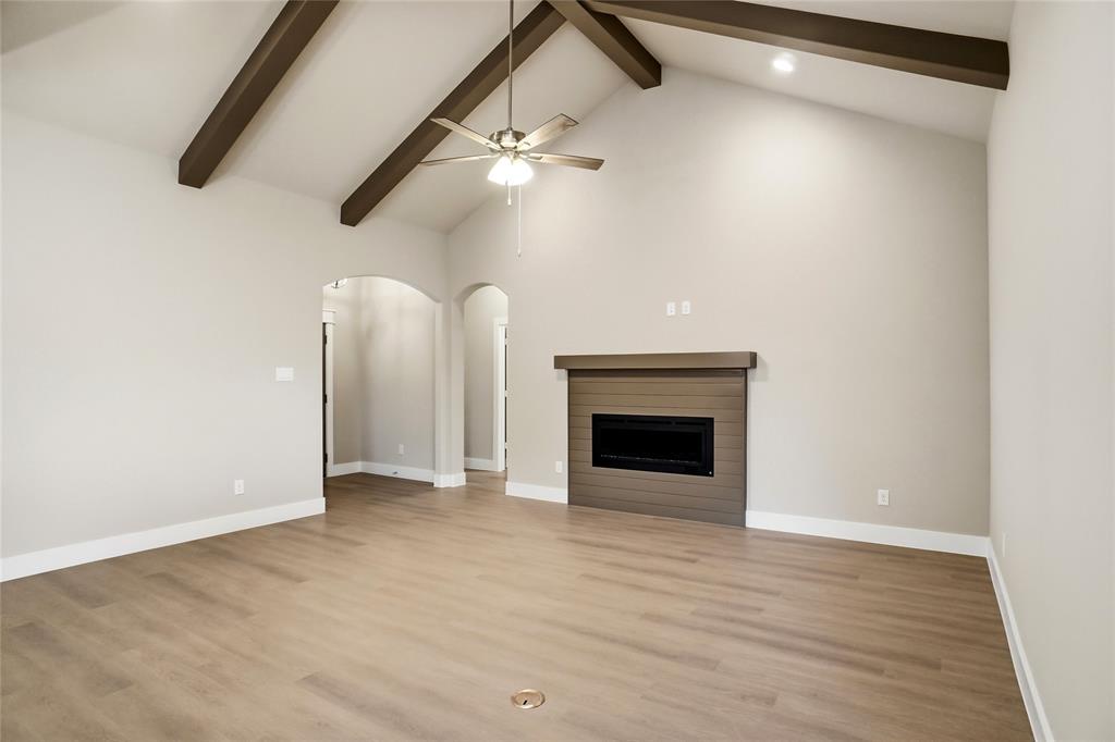 133 Joel Street Springtown, TX 76082 - Photo 3 of 15 an empty room with windows fireplace and a ceiling fan