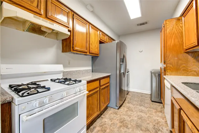 a kitchen with stainless steel appliances granite countertop a stove a refrigerator and a stove