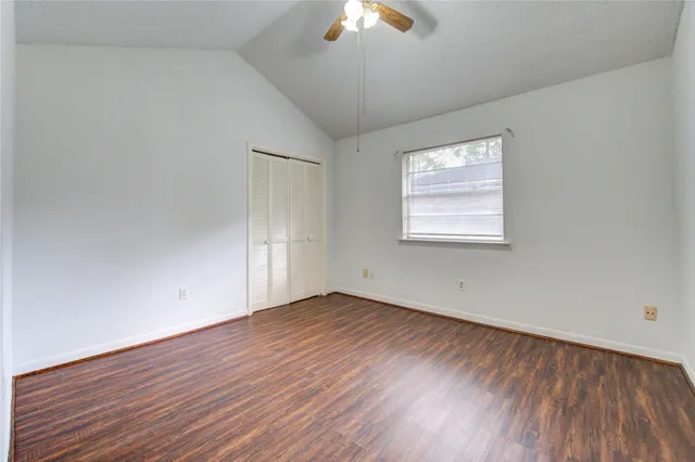 an empty room with wooden floor chandelier fan and windows