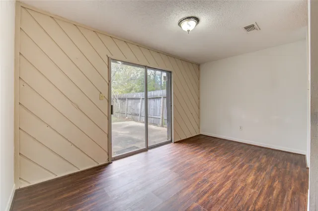 an empty room with wooden floor and windows with curtains