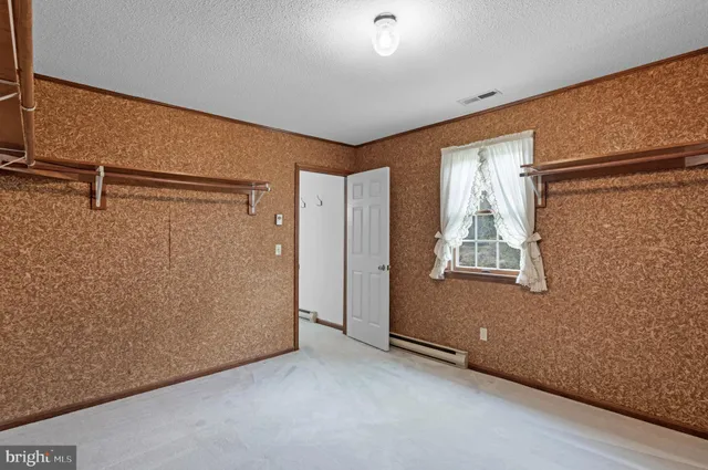 an empty room with windows and view of kitchen