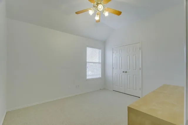 a view of an empty room with window and chandelier fan