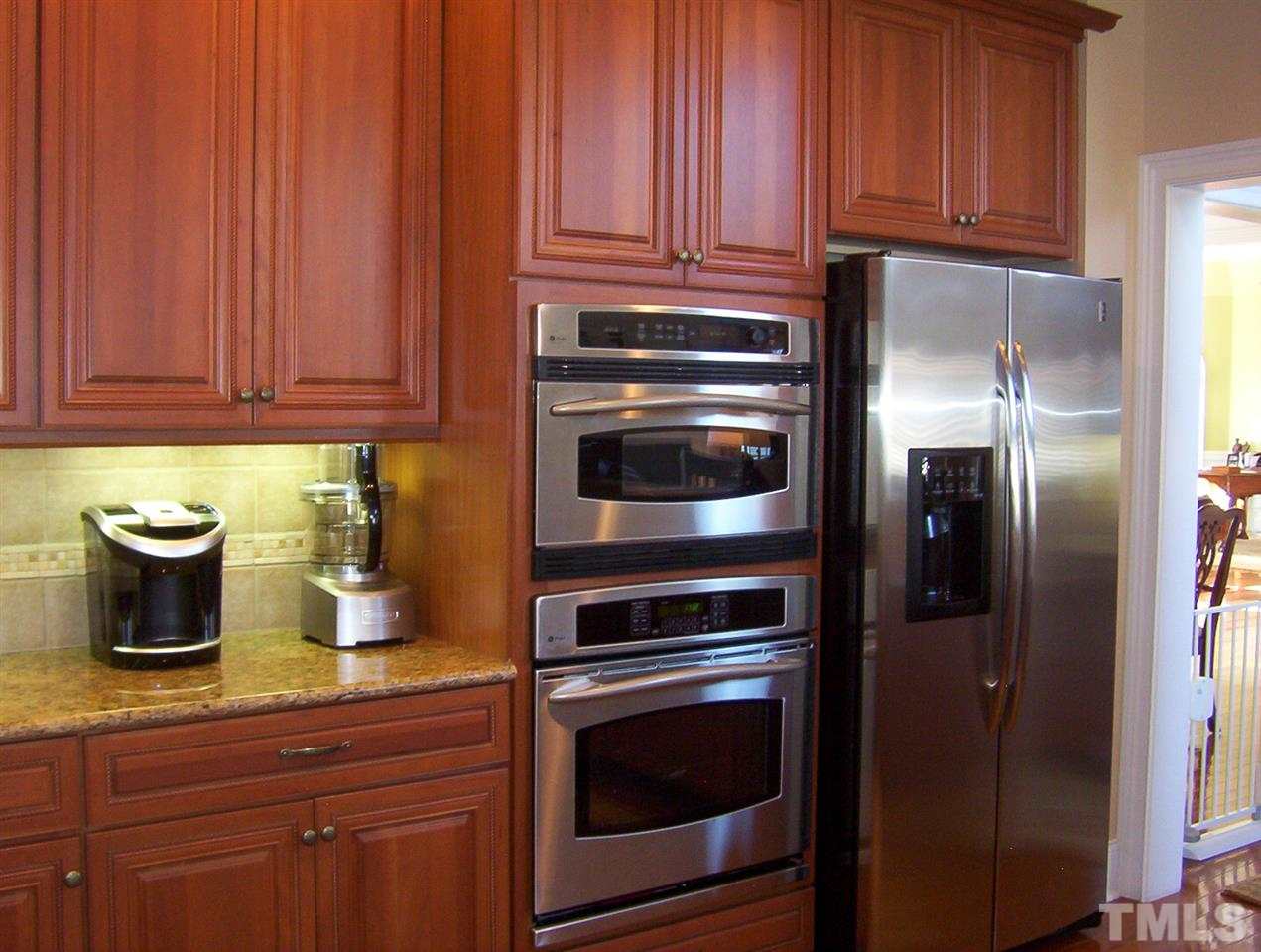 10652 Tarton Fields Circle Raleigh, NC 27617 - Photo 7 of 25 a kitchen with granite countertop stainless steel appliances and wooden cabinets