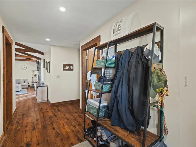a walk in closet with wooden floor and a bathroom