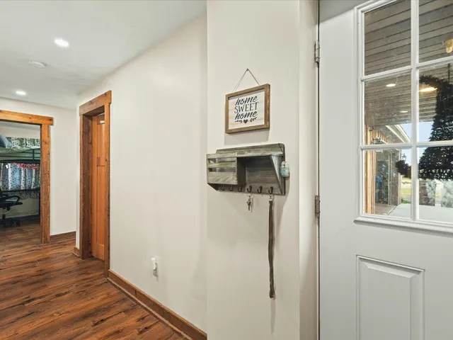 a view of a hallway with wooden floor and a flat screen tv