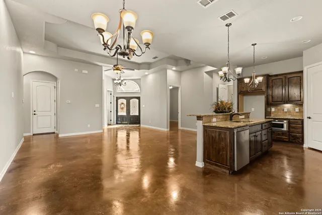 an empty room with wooden floor chandelier fan and windows