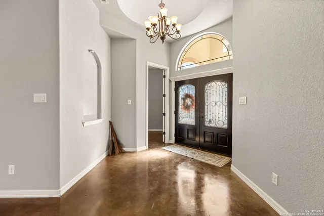 a view of a livingroom with a kitchen island stainless steel appliances wooden floor furniture and a chandelier