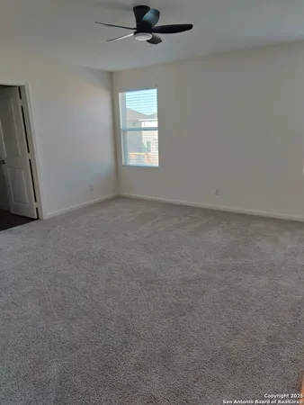 an empty room with windows and ceiling fan